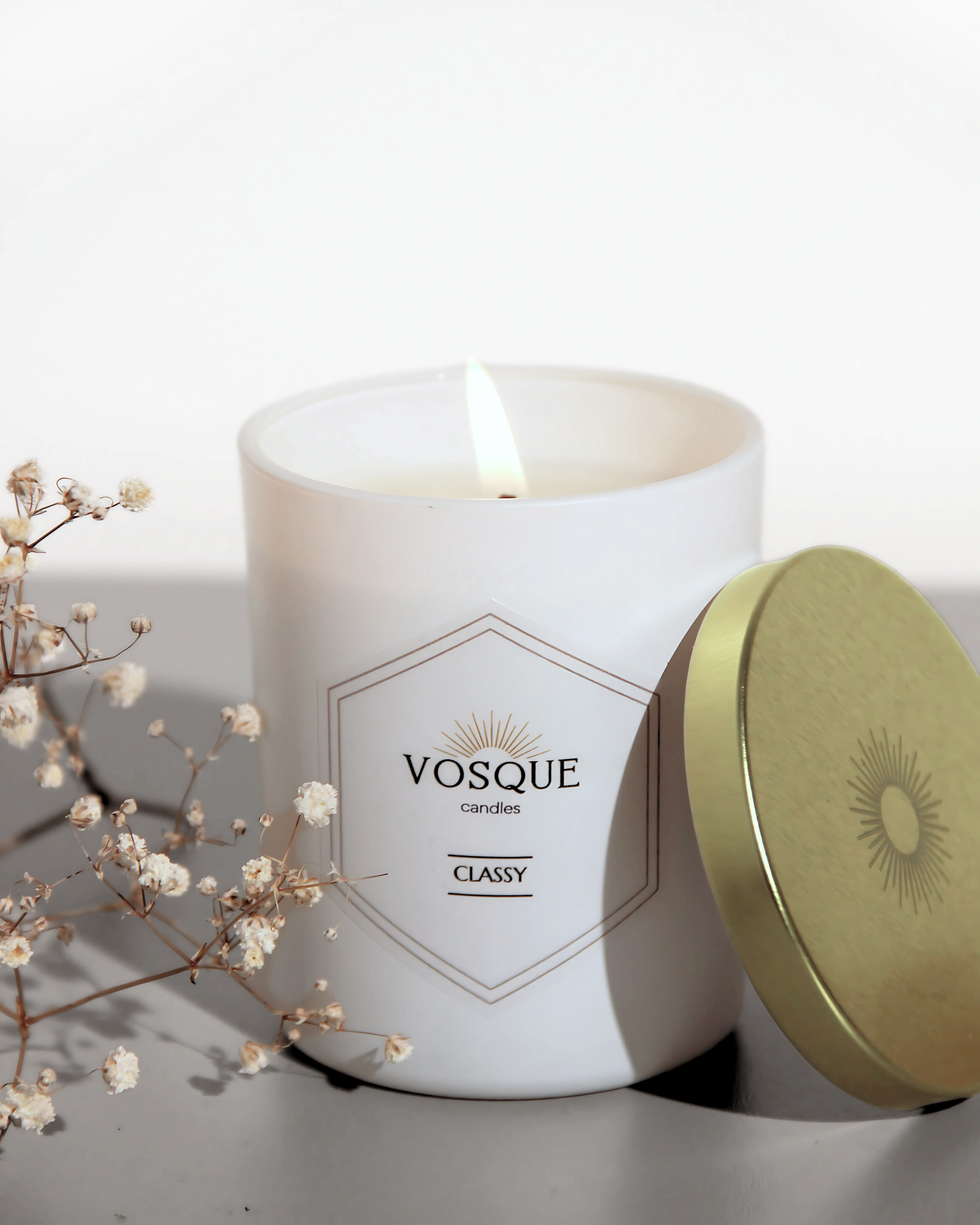 Zapalona świeca CLASSY z bielonego wosku pszczelego w białym szkle z złotą pokrywką i gałązką gipsówki - VOSQUE candles